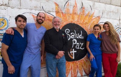 Group of dentist standing against a wall painted with the sun