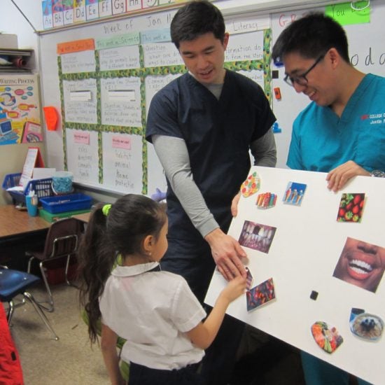 Dentist at a school showing a child a poster