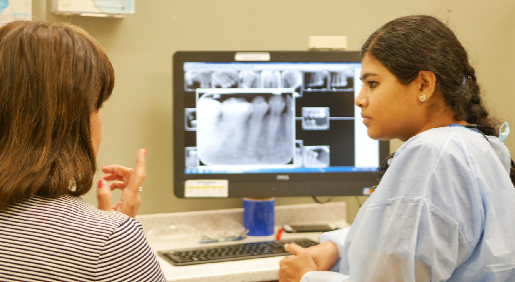 dentist talking to patient in front of computer screen