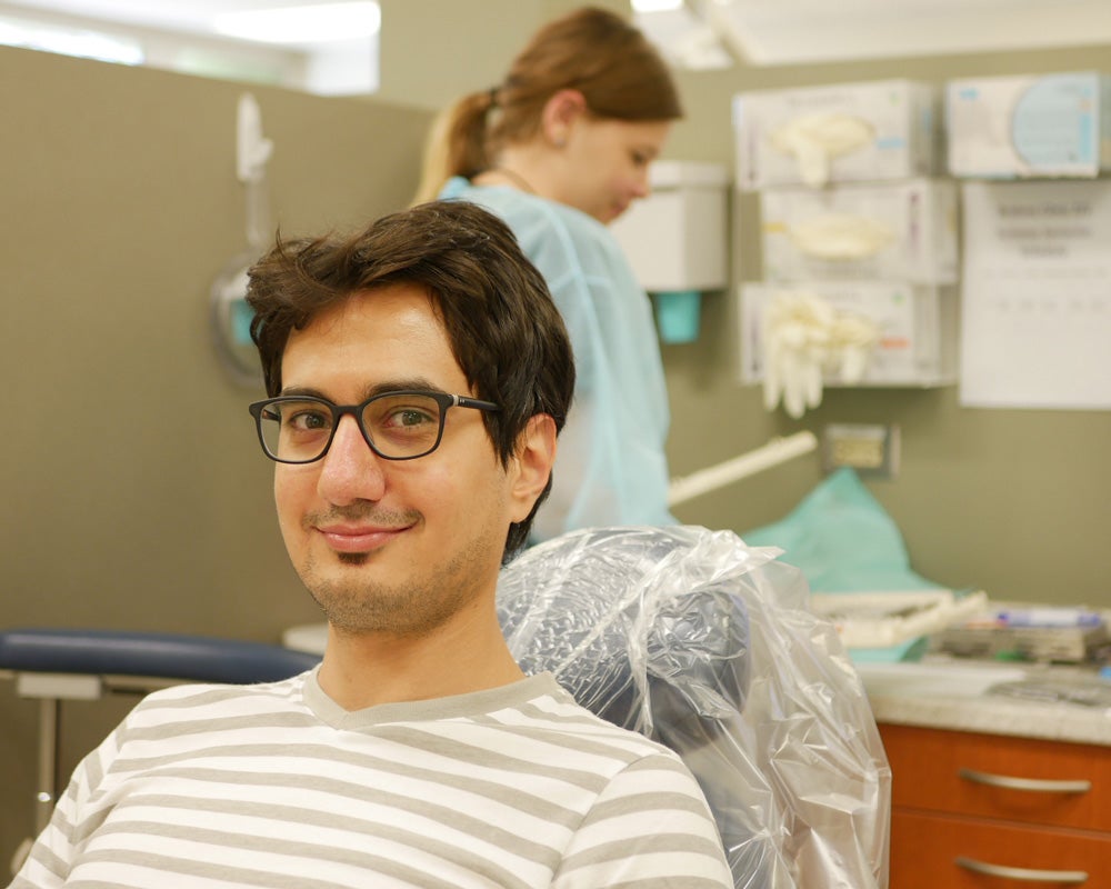 patient smiling at camera with dentist in background