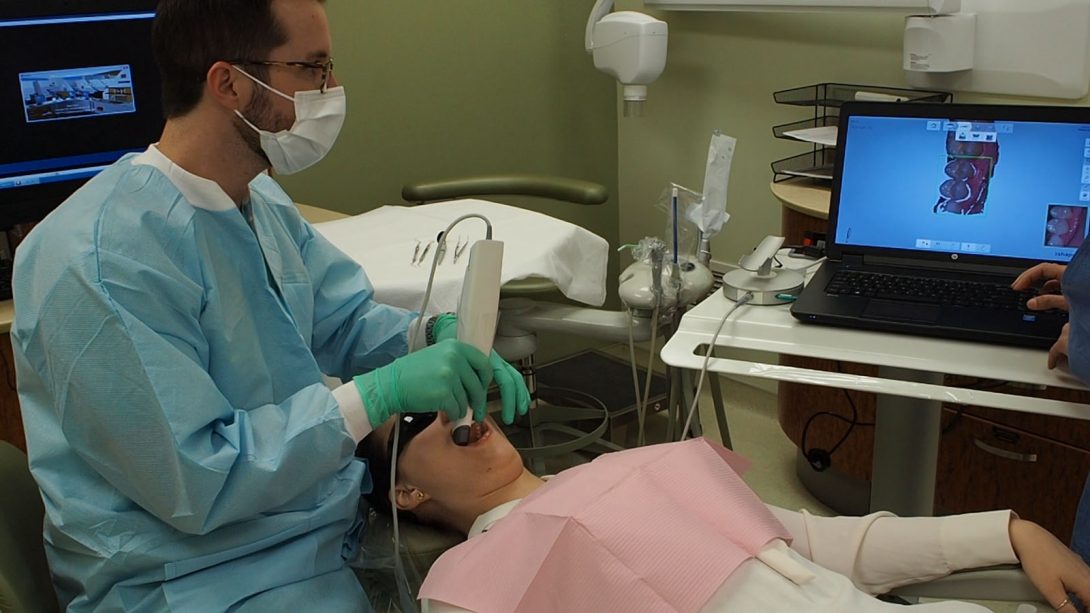 dentist looking at computer screen while working with patient
