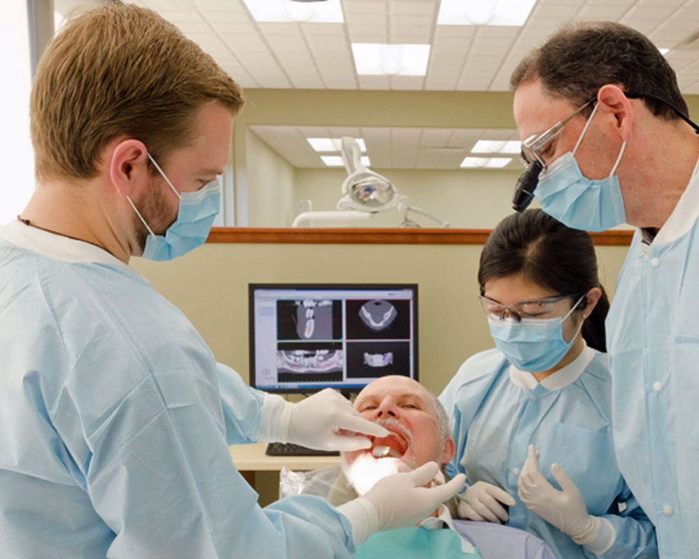 three dentists working with a patient