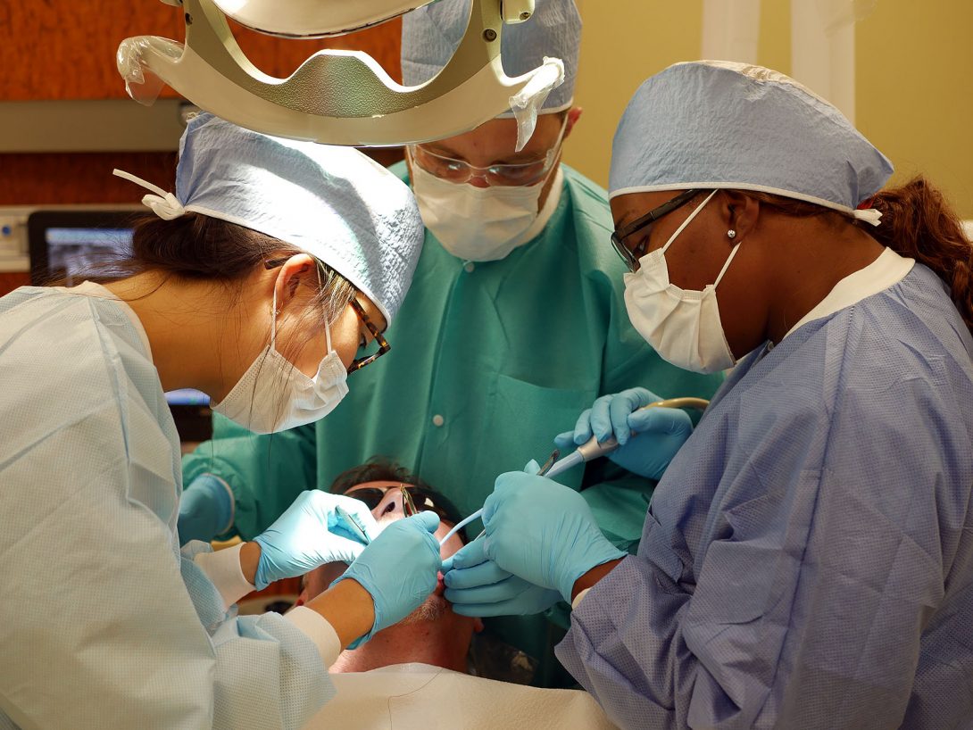 three dentists working on a patient