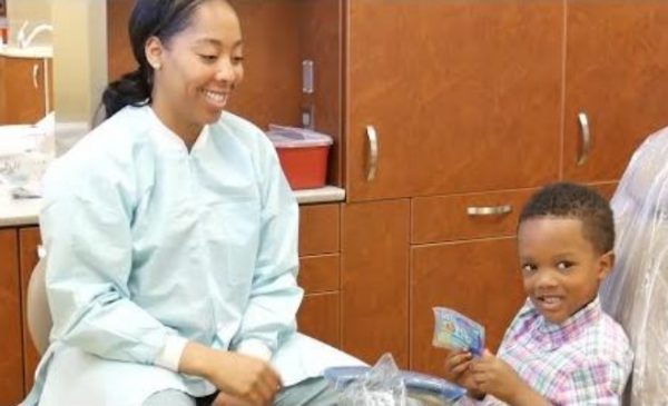 a dentist sitting with a child smiling