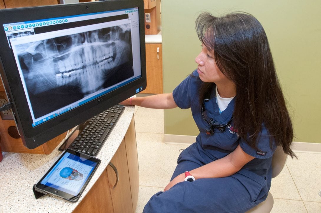 dentist looking at x-rays of teeth on computer screen