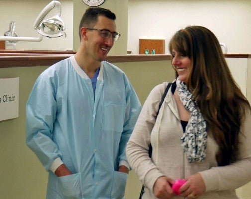 Male resident smiling at female patient in dental office