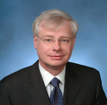 Dr. Graham wearing a black suit and a blue tie 