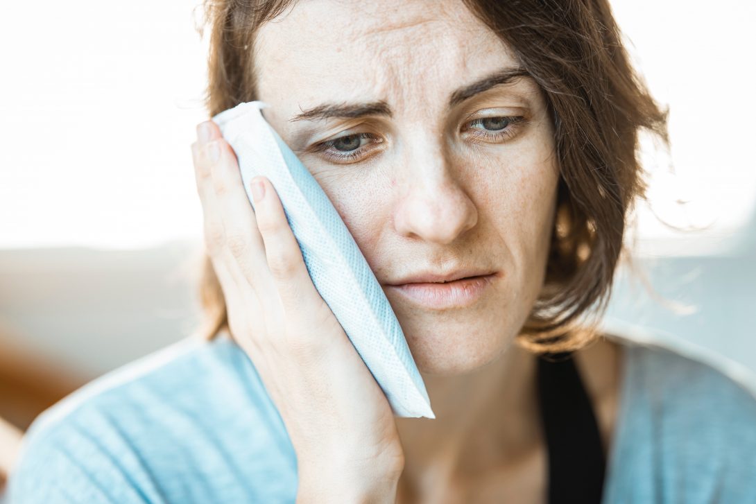 woman holding an ice pack to her cheek