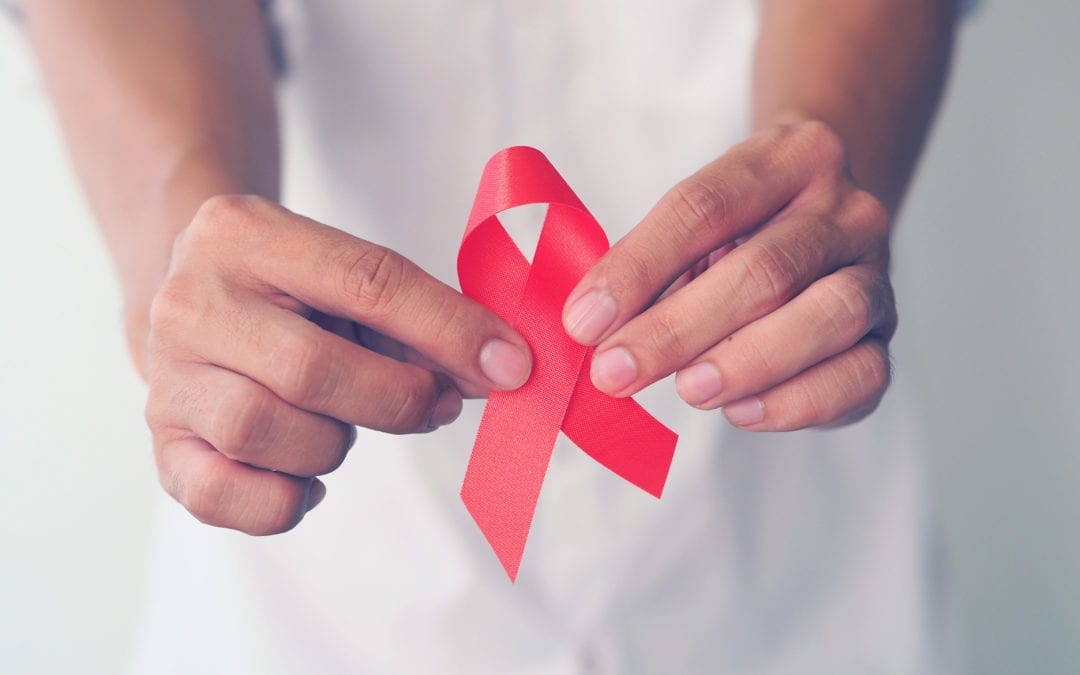 person holding a red ribbon for HIV awareness