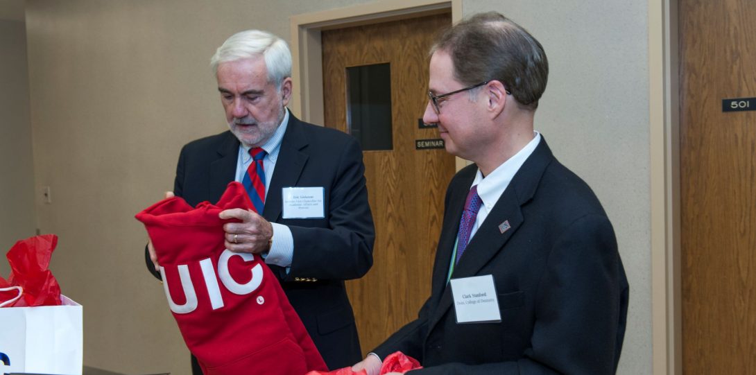 Dean Stanford receiving a bright red UIC crewneck at his welcome ceremony