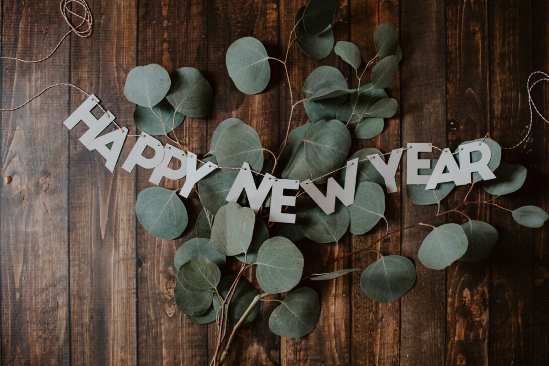 leaves on a wooden desk with a sign that reads happy new year