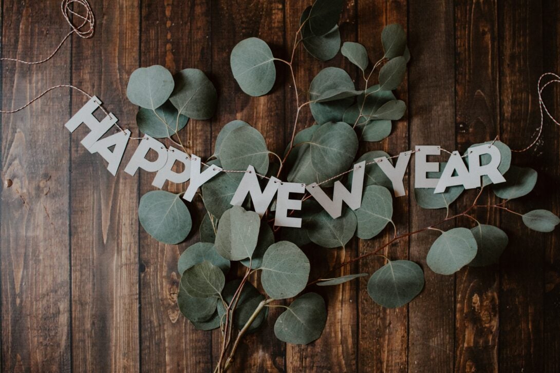 leaves on a wooden desk with a sign that reads happy new year