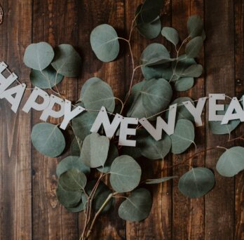 leaves on a wooden desk with a sign that reads happy new year 