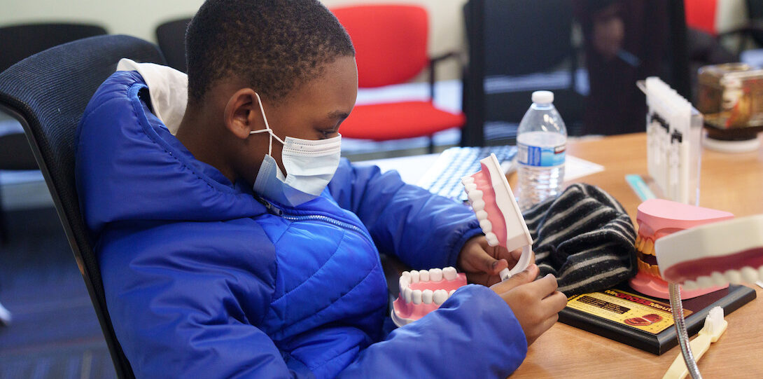 Young boy in blue winter coat using a dental mold