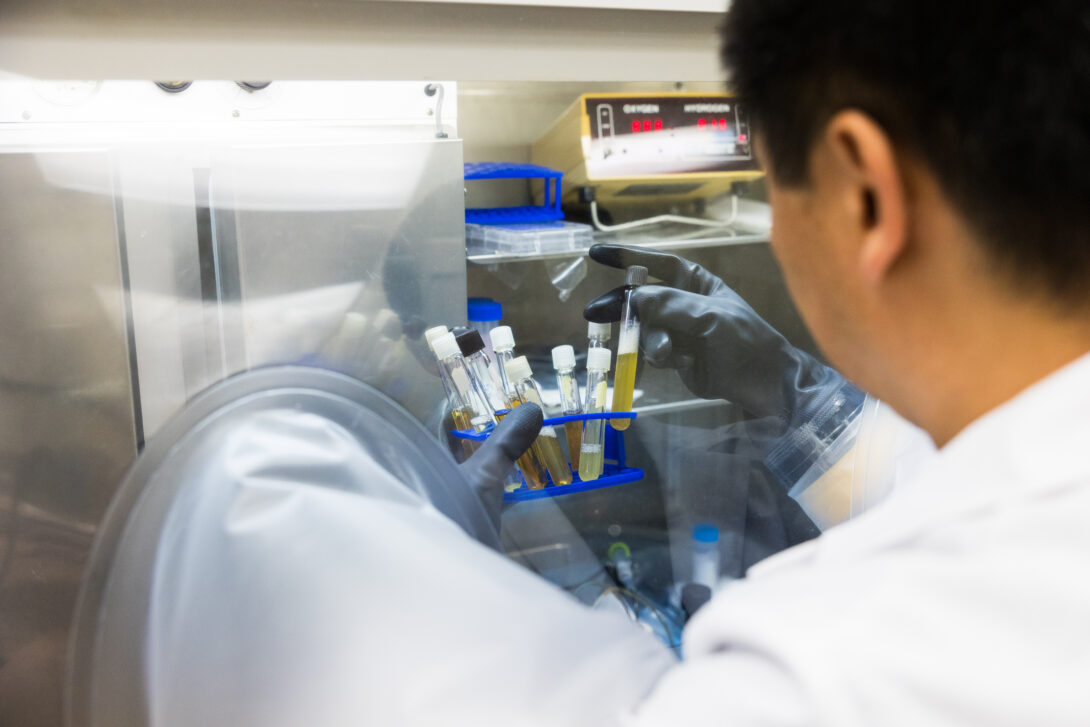 researcher in white coat removing test tubes from machine