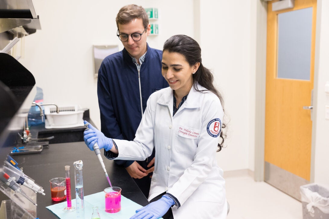 women wearing a lab coat transferring liquid into a syringe