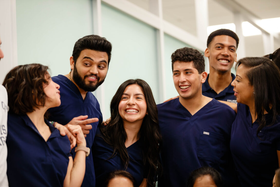 Group of students smiling in navy blue scrubs
