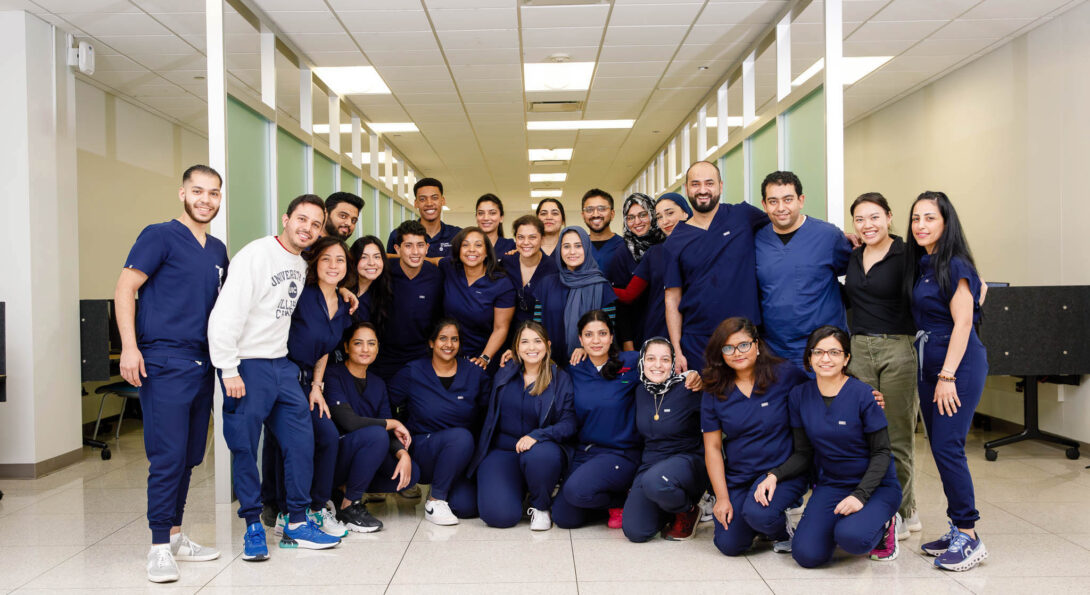 Students in blue scrubs posing in the common area