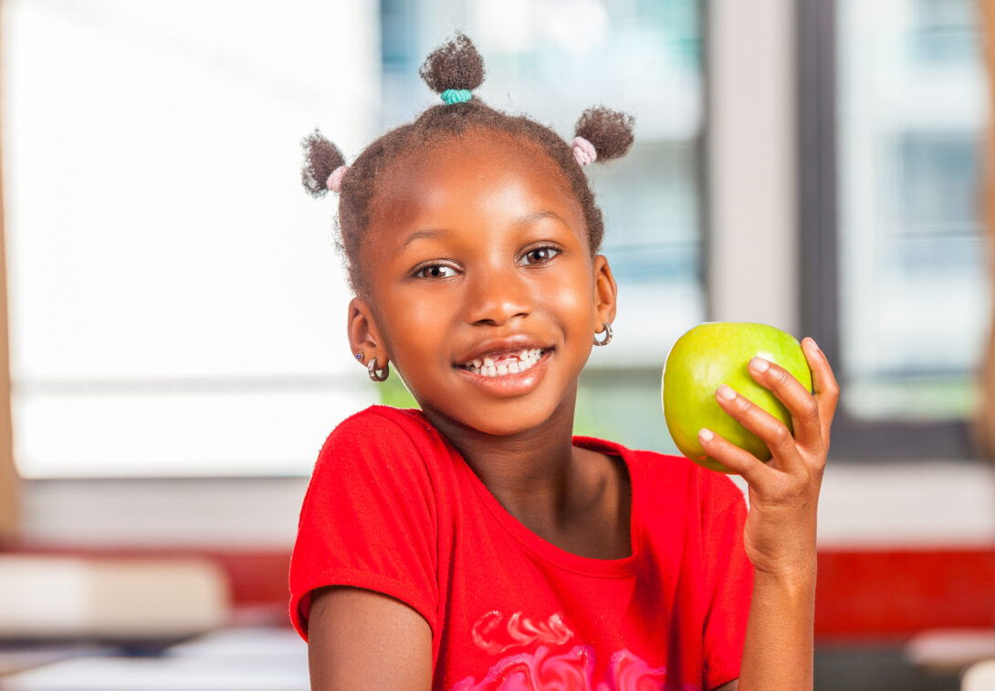 Child smiling and with an apple