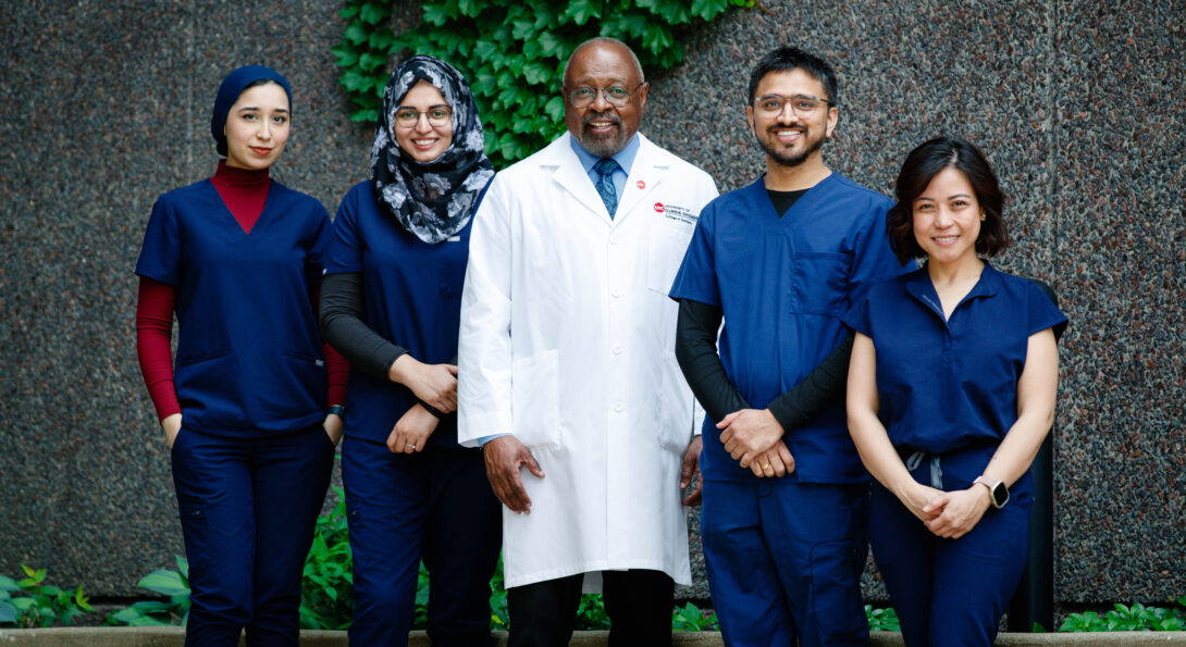 Dr. Darryl Pendleton posing with four students in front of the College of Dentistry building