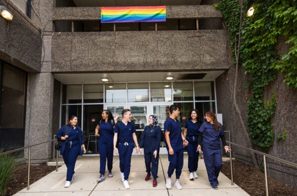 Students in from of building with LGBTQ+ flag