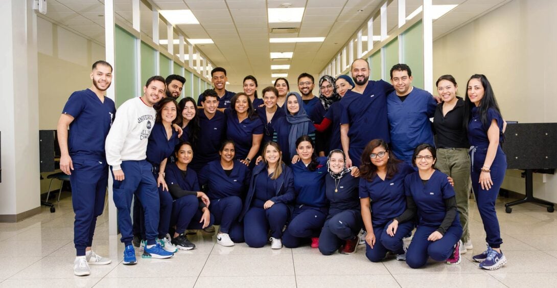 Group of students smiling in navy blue scrubs