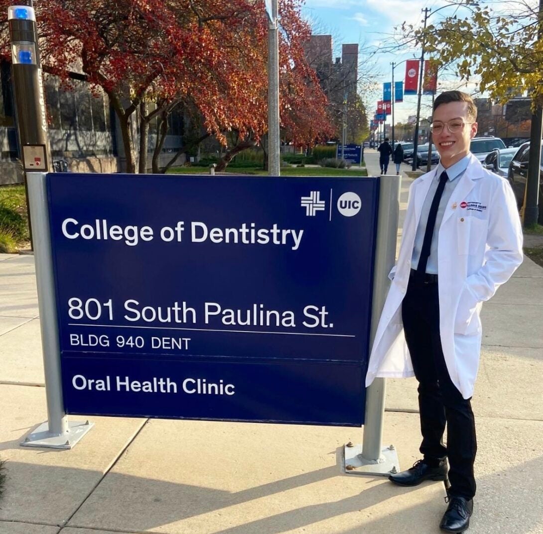 Student Samuel Romo in front College of Dentistry sign