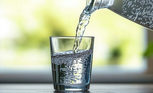 Water pouring from pitcher to a clear glass