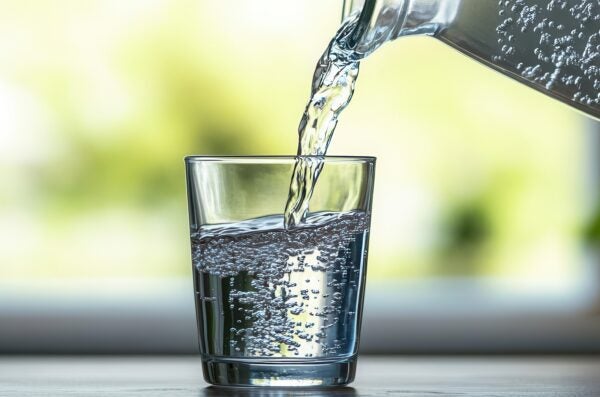 Water pouring from pitcher to a clear glass