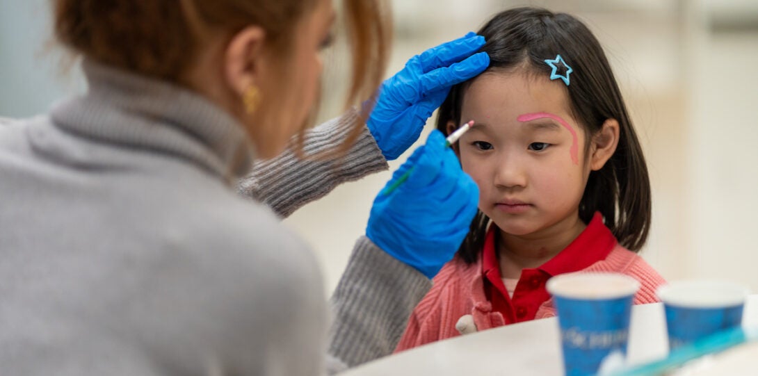 School child gets face painted by student volunteer