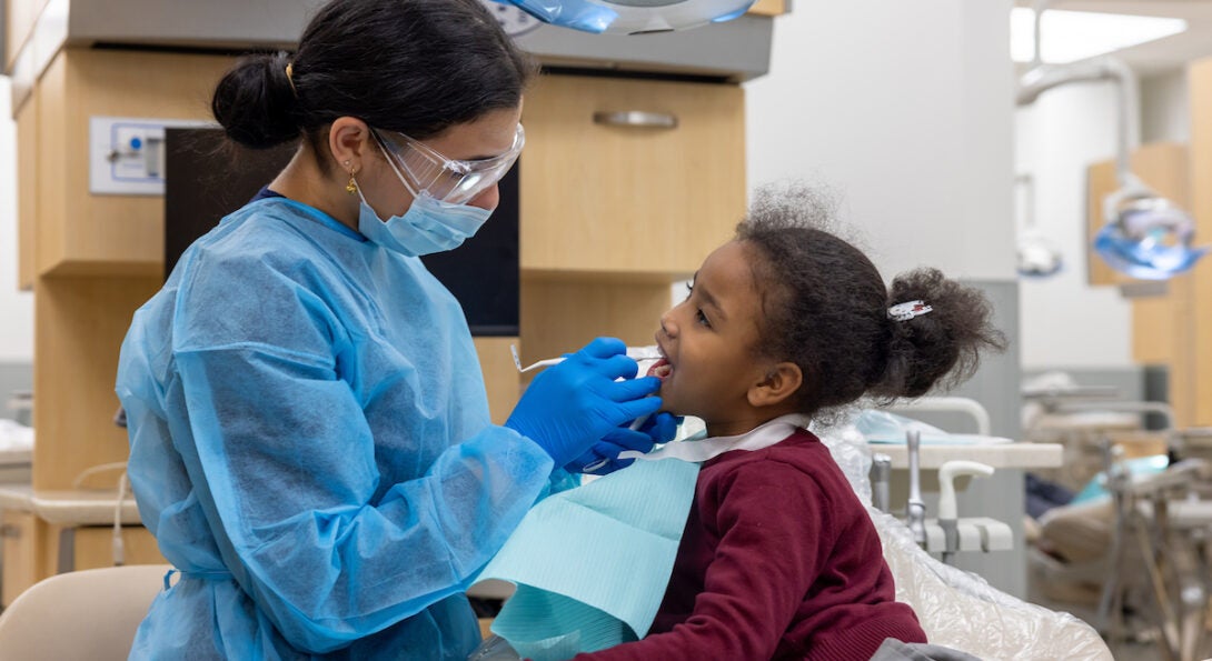 Young school girl receives oral exam in dental chair