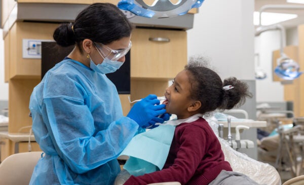 Young school girl receives oral exam in dental chair