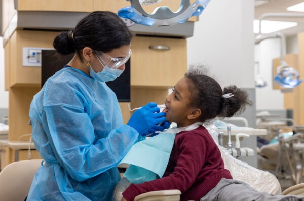 Young school girl receives oral exam in dental chair