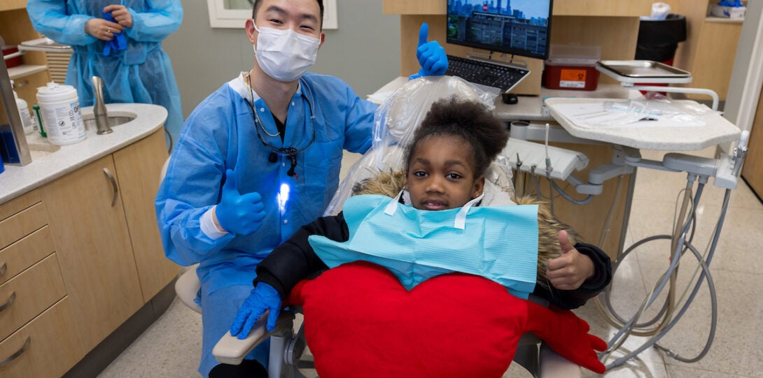 Dentist and child patient thumbs up pose in dental chair