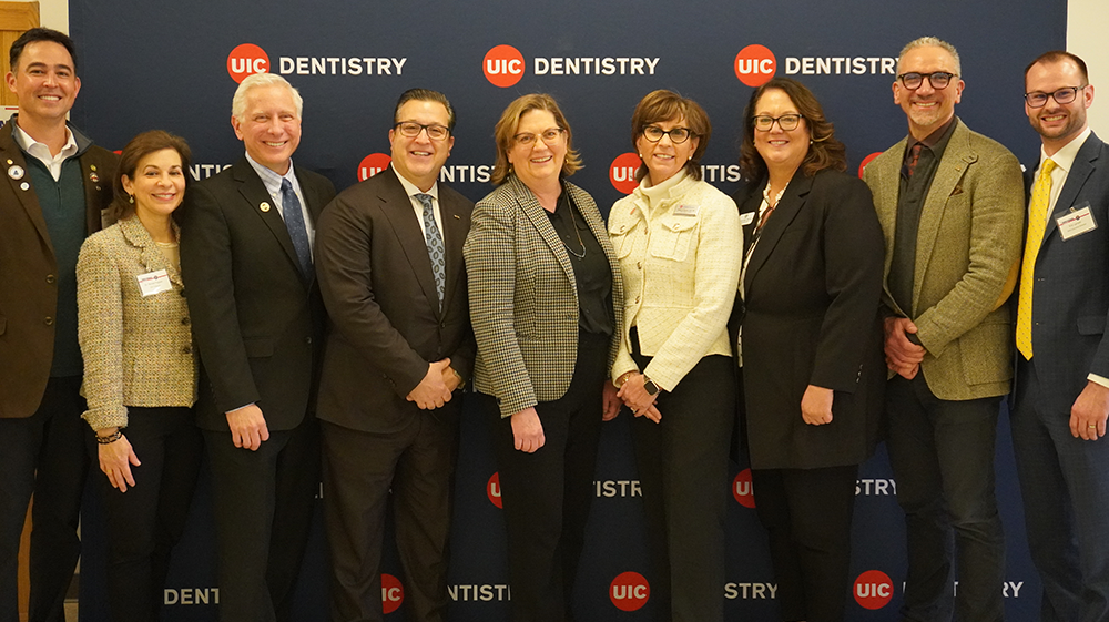 Nine dental organization officers pose in front of blue UIC Dentistry backdrop