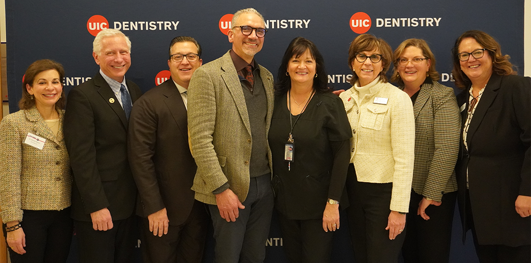 Eight dental organization officers pose in front of blue UIC Dentistry backdrop