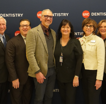 Group of 8 dental organization leaders posed in front of UIC Dentistry blue backdrop 