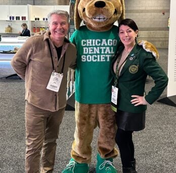 Man and woman pose with Chicago Dental Society mascot Hadley 
